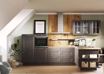 Landhausküche in schwarz mit Dachschräge, heller Holzarbeitsplatte und Holznischenrückwand. Küche mit Dachschräge