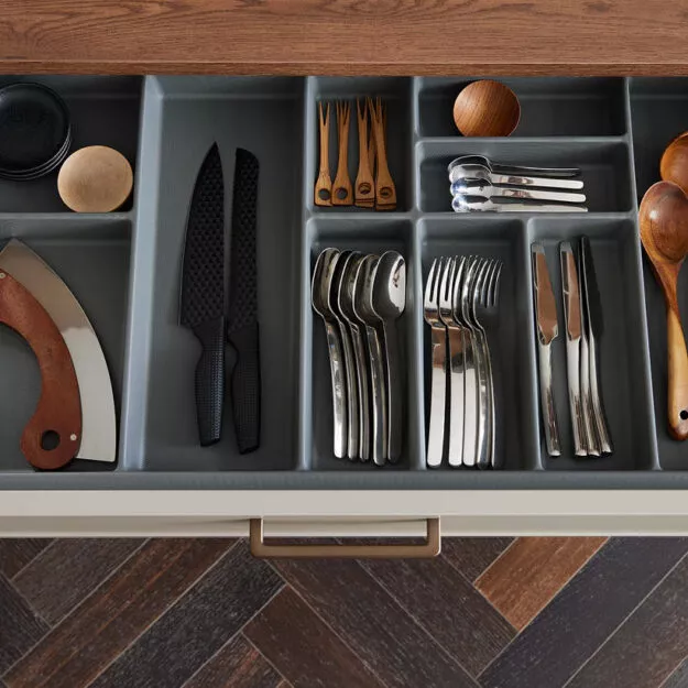 Besteckeinsatz in Küchenschublade mit übersichtlich sortierten Messern, Gabeln, Löffeln und Küchenutensilien in modernem Design