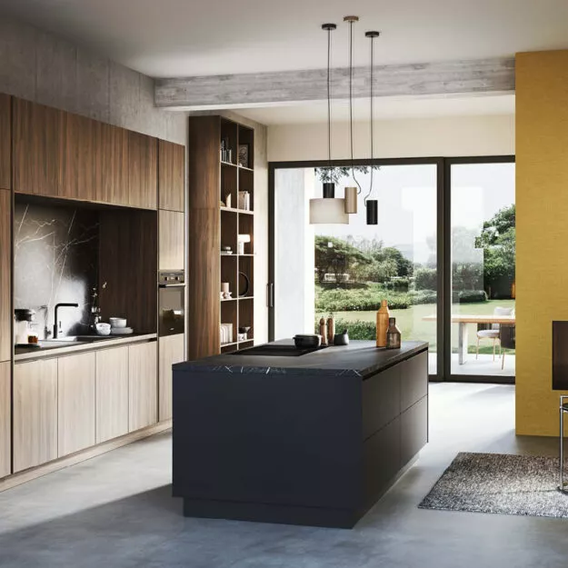 Offene Designküche mit dunkler Kochinsel, Holz- und Steinoptik sowie großen Fensterfronten und minimalistischer Pendelbeleuchtung