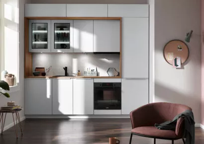 Moderne Pantryküche in Weiß mit Holzrahmen, integrierter Spüle, Backofen und beleuchteten Hängeschränken, kompakt und ideal für kleine Wohnräume.