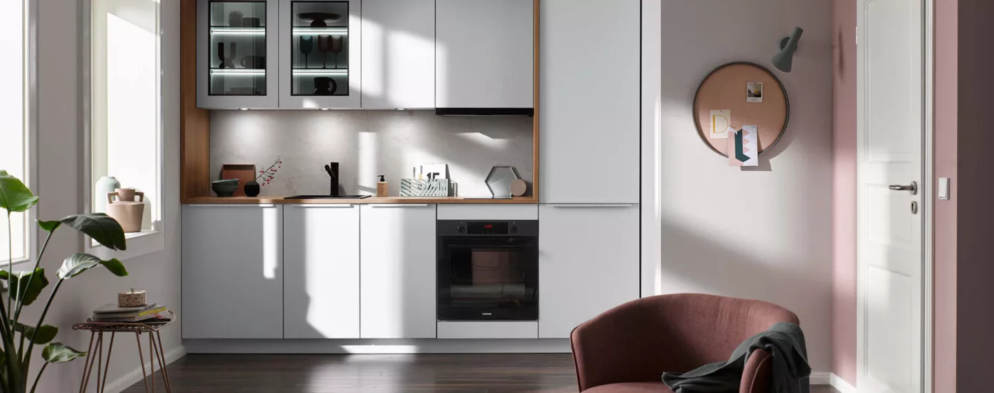 Minimalistische Pantryküche in Weiß mit Holzdetails, integriertem Backofen und Spüle, funktional und stilvoll für kleine Apartments und Pantrylösungen.