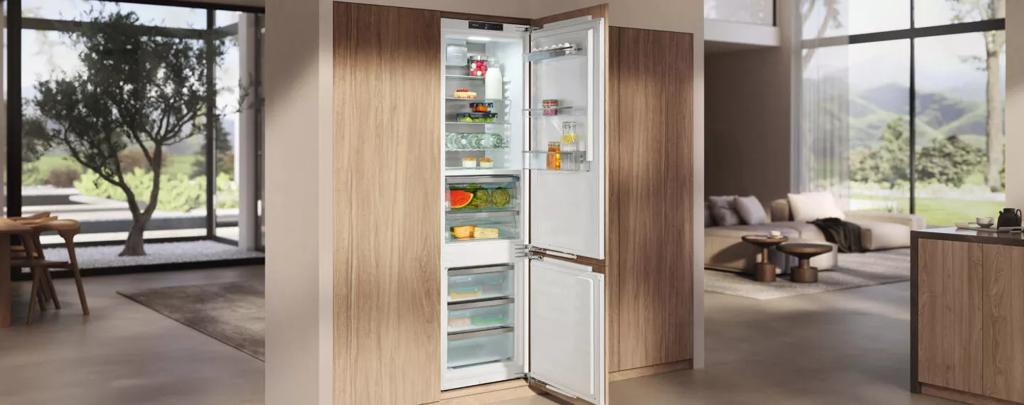 Offener Einbau-Kühlschrank mit Gefrierfach, weißem Innenraum und Holzfront in moderner Küche zur frischen Lebensmittelaufbewahrung.