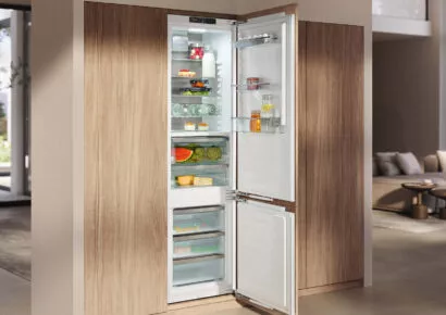 Offener Einbau-Kühlschrank mit Gefrierfach, weißem Innenraum und Holzfront in moderner Küche zur frischen Lebensmittelaufbewahrung.