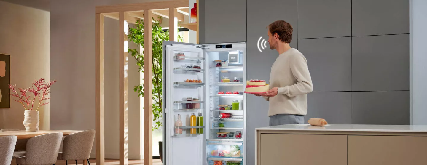 Offener Einbau-Kühlschrank in eleganter Küchenzeile mit frischem Obst, Gemüse und Getränken für eine stilvolle Lebensmittelaufbewahrung.